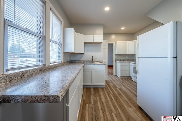 kitchen featuring white cabinets, hardwood / wood-style floors, white appliances, and sink