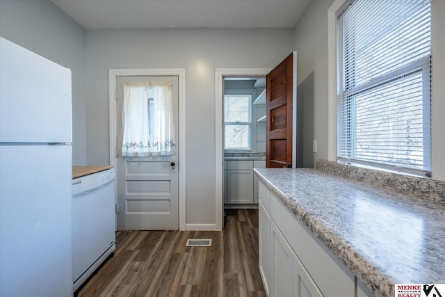 kitchen with plenty of natural light, white cabinetry, dark hardwood / wood-style flooring, and white appliances