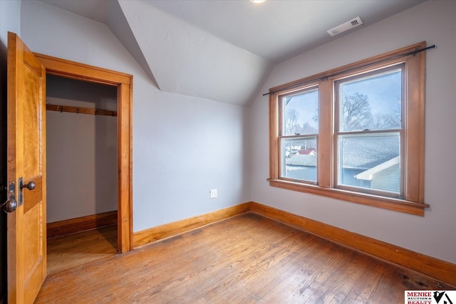 additional living space with light hardwood / wood-style flooring and vaulted ceiling