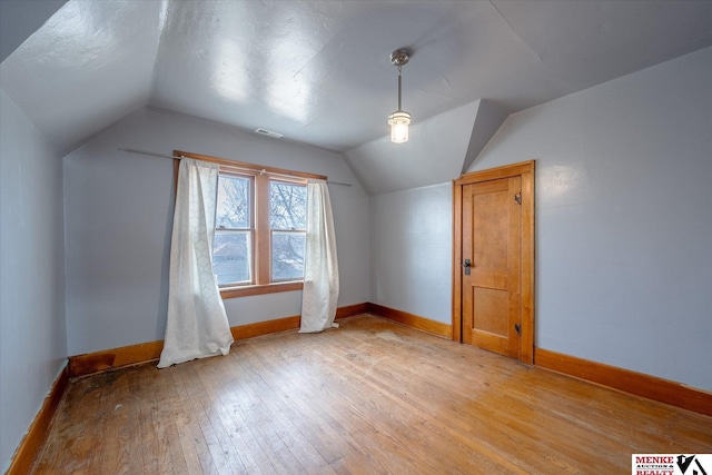 additional living space with wood-type flooring and vaulted ceiling