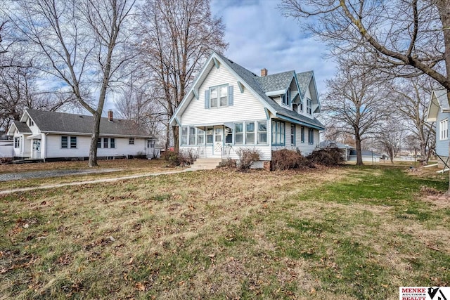 view of front of property featuring a sunroom and a front lawn