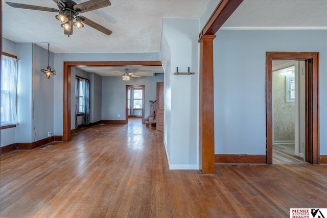 interior space with hardwood / wood-style flooring, ceiling fan, ornamental molding, and a textured ceiling