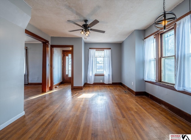 interior space with ceiling fan with notable chandelier, dark hardwood / wood-style flooring, and a textured ceiling