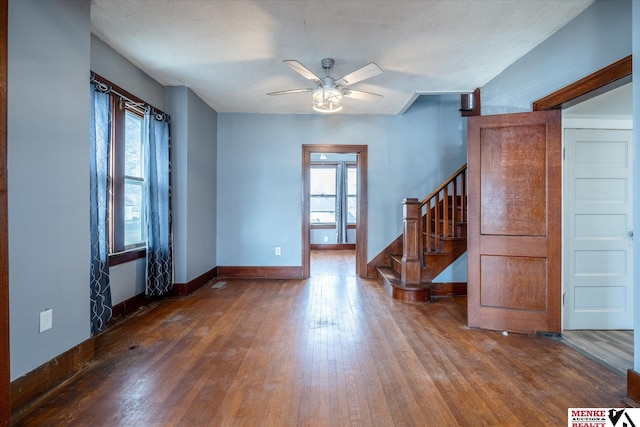 unfurnished living room featuring a textured ceiling, ceiling fan, and dark wood-type flooring