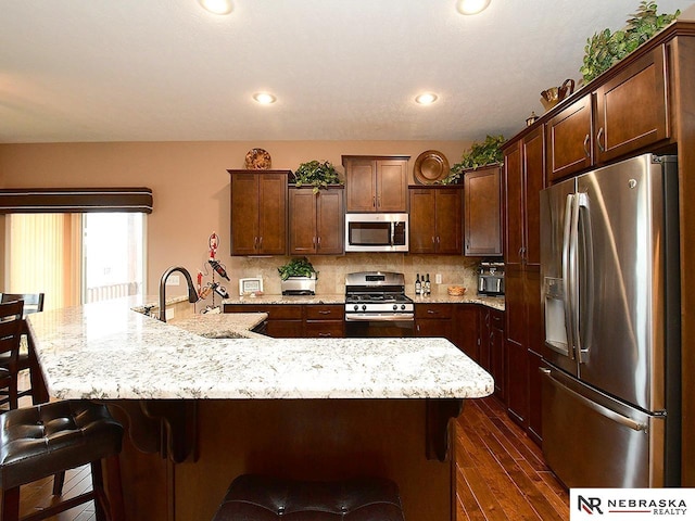 kitchen featuring stainless steel appliances, dark brown cabinets, an island with sink, and sink