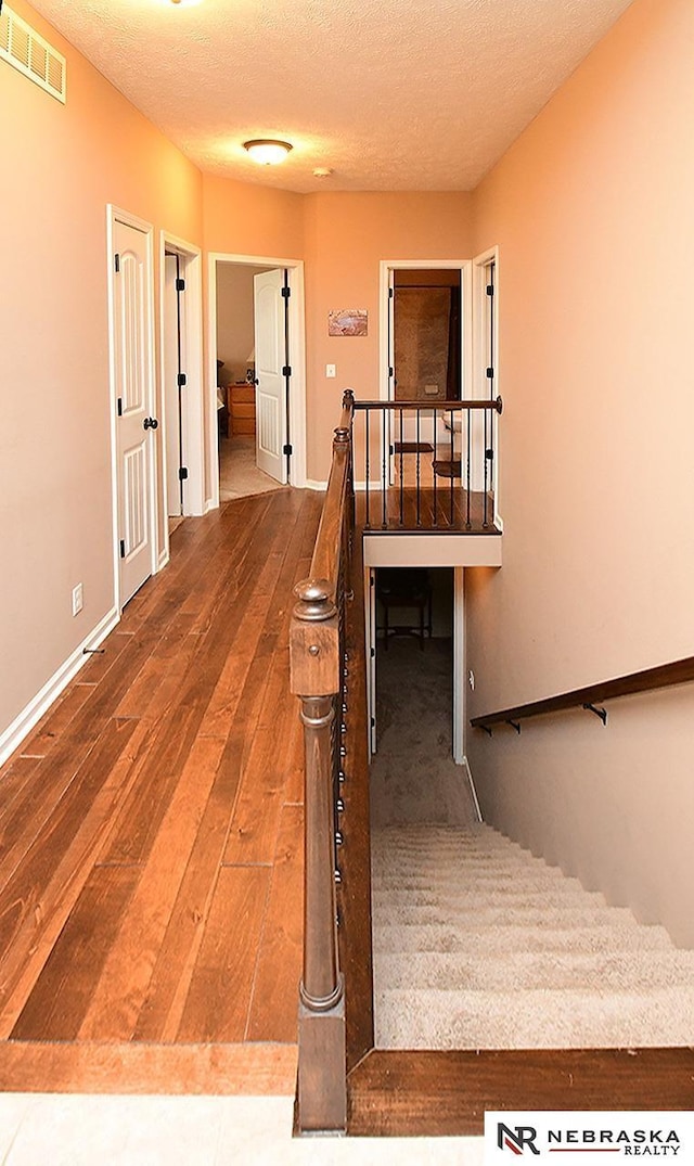 stairs featuring hardwood / wood-style flooring and a textured ceiling