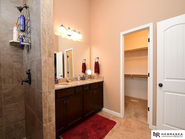 bathroom featuring tile patterned flooring, tiled shower, and vanity