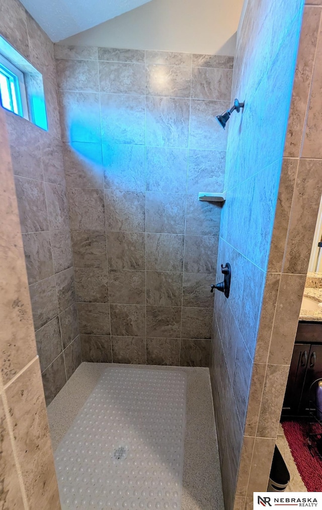 bathroom featuring a tile shower and vanity