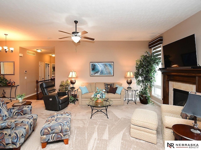 carpeted living room featuring ceiling fan with notable chandelier, a tile fireplace, and a healthy amount of sunlight