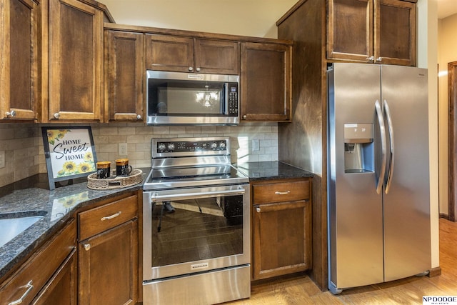 kitchen with decorative backsplash, light wood-type flooring, appliances with stainless steel finishes, and dark stone counters