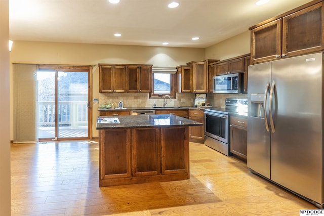 kitchen with a center island, stainless steel appliances, light hardwood / wood-style flooring, and tasteful backsplash