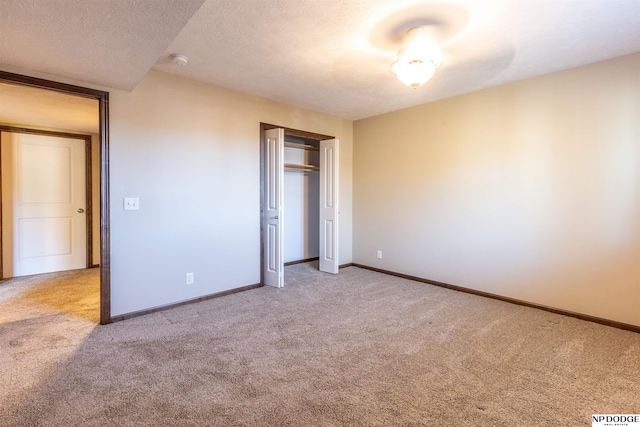 unfurnished bedroom with light colored carpet, a textured ceiling, and a closet