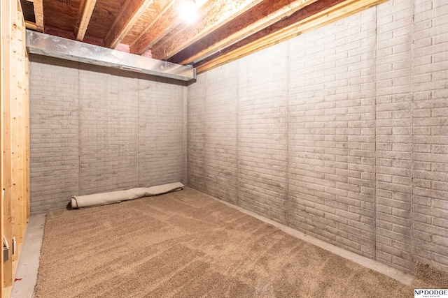 basement featuring carpet floors and brick wall