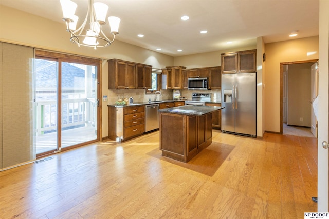 kitchen featuring pendant lighting, sink, light hardwood / wood-style flooring, a kitchen island, and stainless steel appliances