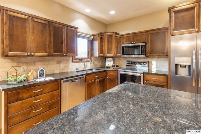 kitchen featuring backsplash, sink, dark stone counters, and stainless steel appliances