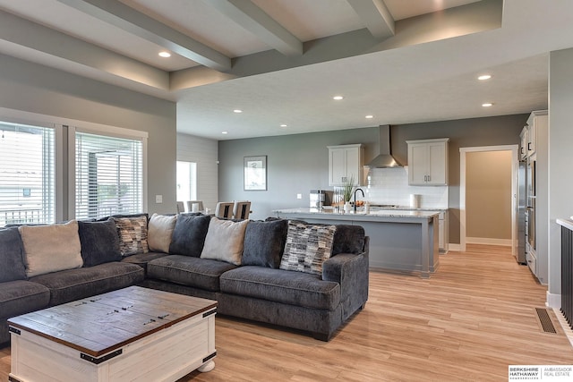 living room with beamed ceiling and light hardwood / wood-style flooring