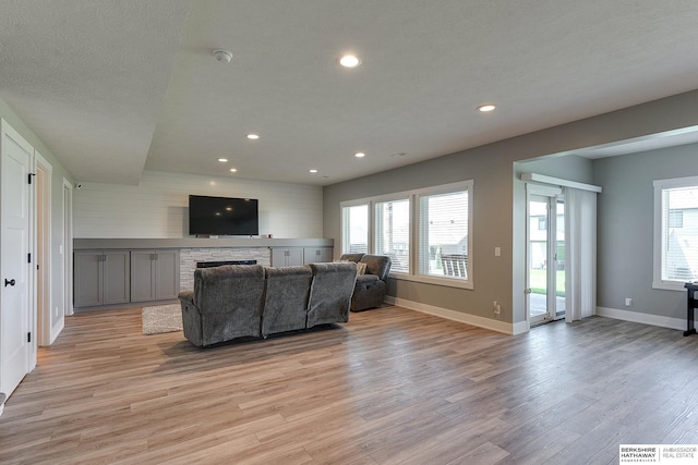 living room featuring a fireplace, a textured ceiling, and light hardwood / wood-style flooring