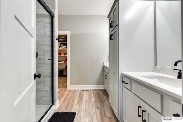 bathroom with walk in shower, vanity, a textured ceiling, and hardwood / wood-style flooring