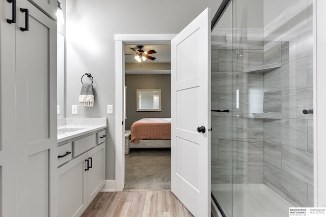 bathroom featuring vanity, ceiling fan, wood-type flooring, and walk in shower