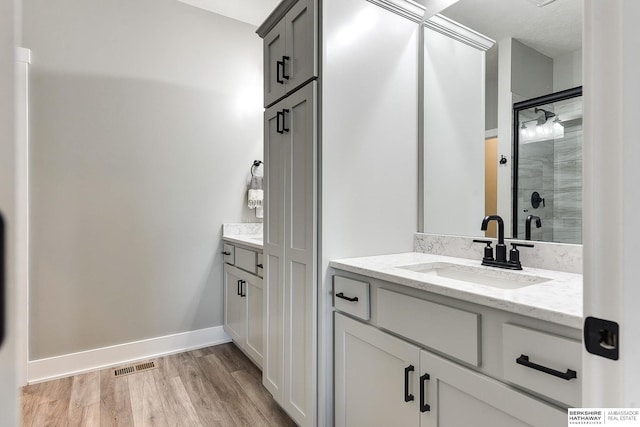 bathroom with hardwood / wood-style floors, vanity, and a shower with shower door