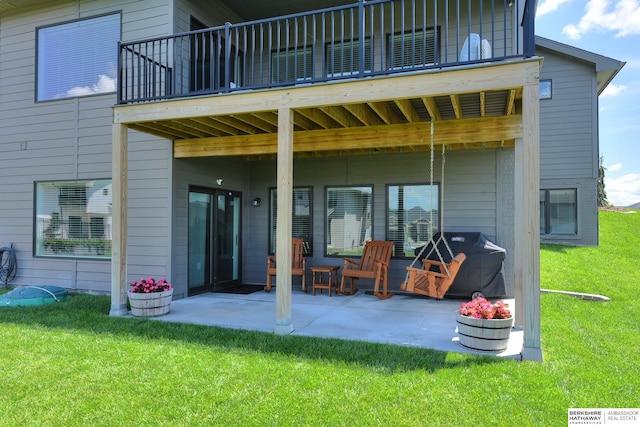 rear view of property with a balcony, a patio area, and a lawn