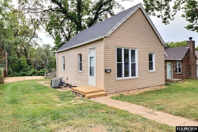 rear view of property featuring a yard and central AC