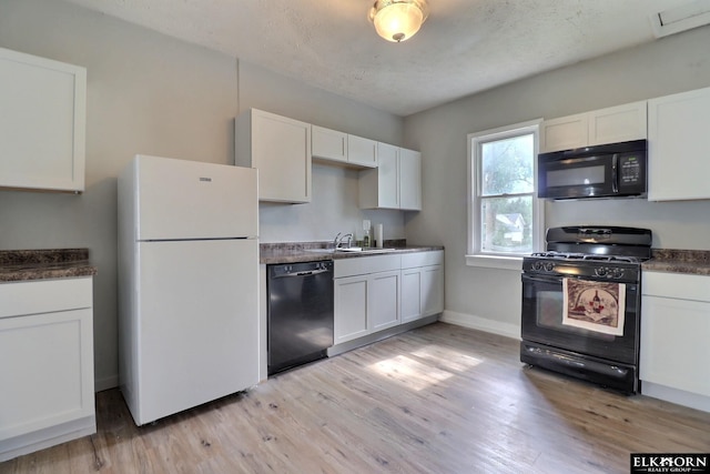 kitchen featuring black appliances, white cabinetry, a textured ceiling, and light hardwood / wood-style flooring