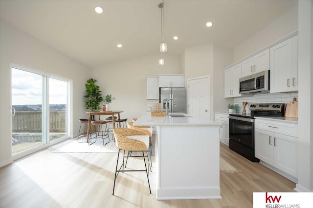 kitchen featuring tasteful backsplash, a kitchen island with sink, vaulted ceiling, and appliances with stainless steel finishes