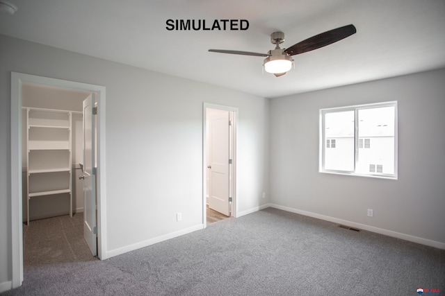 unfurnished bedroom featuring carpet flooring, a walk in closet, ceiling fan, and a closet