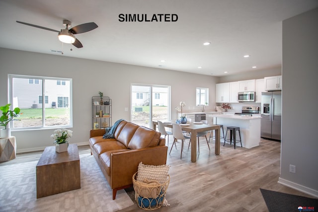 living room featuring light hardwood / wood-style flooring, ceiling fan, and sink