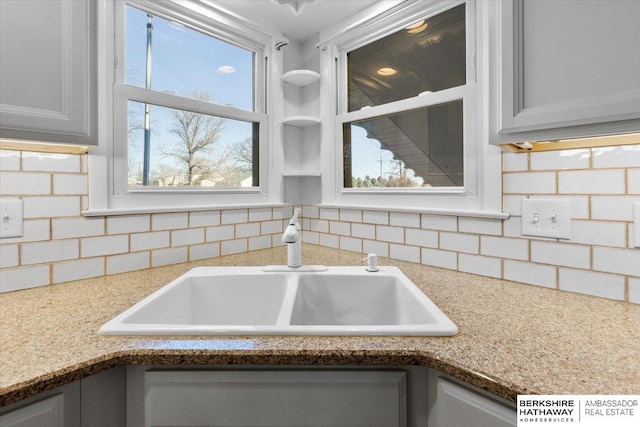 room details featuring white cabinetry, decorative backsplash, and sink