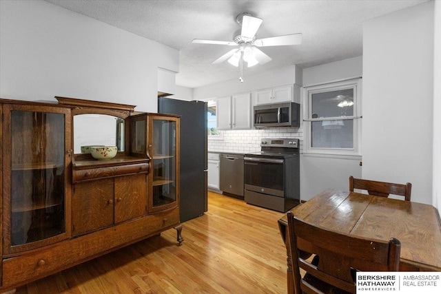 kitchen featuring appliances with stainless steel finishes, light wood-type flooring, tasteful backsplash, ceiling fan, and white cabinetry