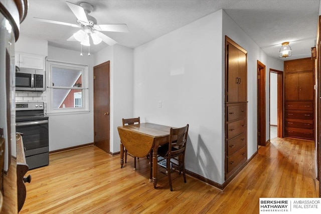 dining area featuring ceiling fan, light wood-type flooring, and a textured ceiling