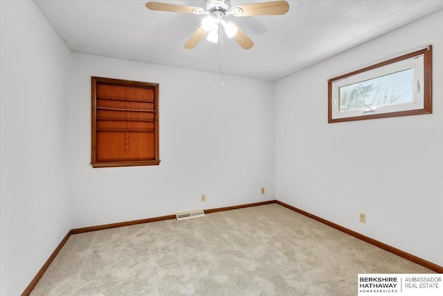 carpeted empty room featuring ceiling fan and built in shelves