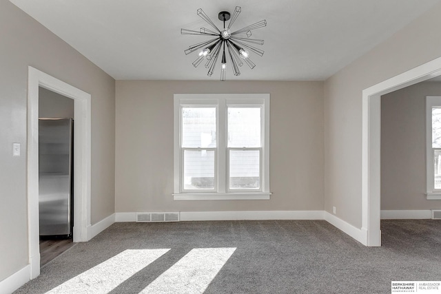 carpeted spare room with a chandelier