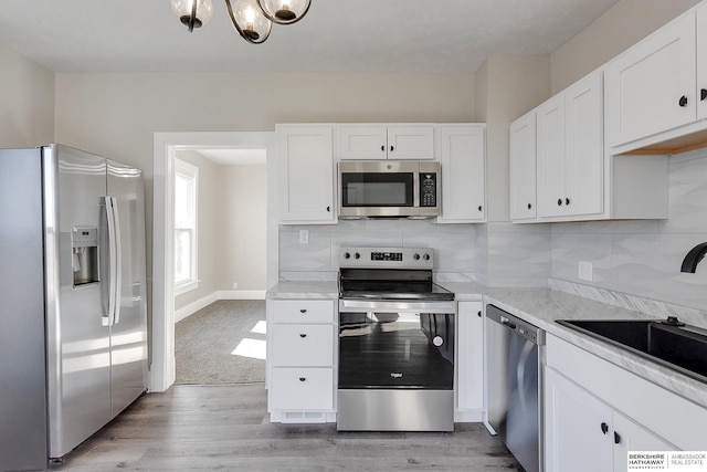 kitchen with white cabinetry, light wood-type flooring, backsplash, and appliances with stainless steel finishes