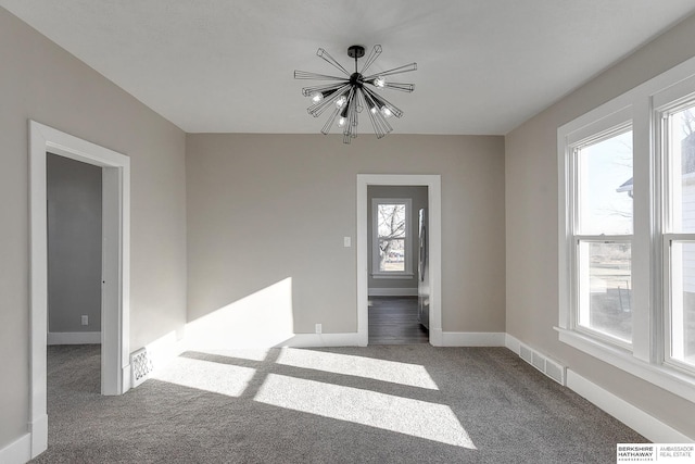 carpeted spare room featuring an inviting chandelier