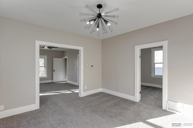 spare room featuring carpet, plenty of natural light, and a notable chandelier