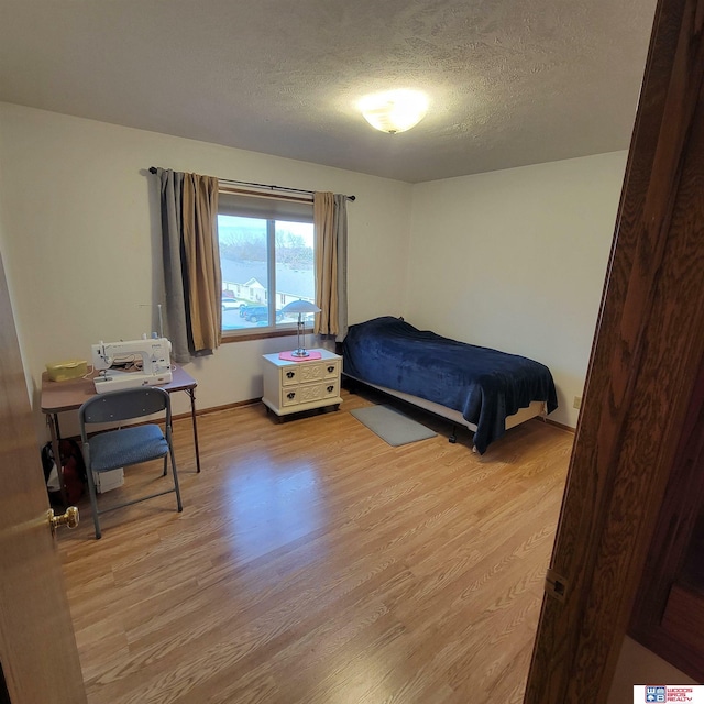 bedroom with a textured ceiling and light wood-type flooring