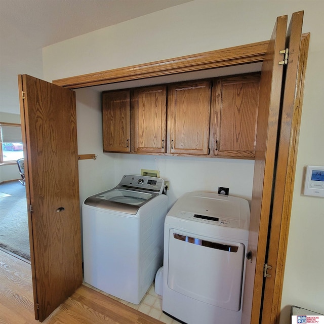 laundry area featuring cabinets, light wood-type flooring, and separate washer and dryer