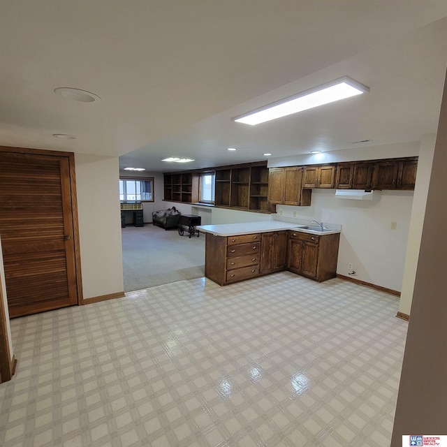 kitchen with light colored carpet, kitchen peninsula, and sink