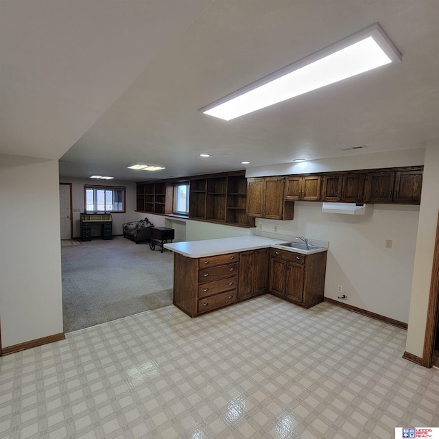 kitchen with kitchen peninsula, light carpet, and dark brown cabinets