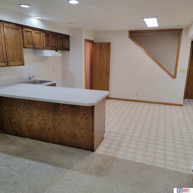 kitchen featuring kitchen peninsula, sink, and light carpet