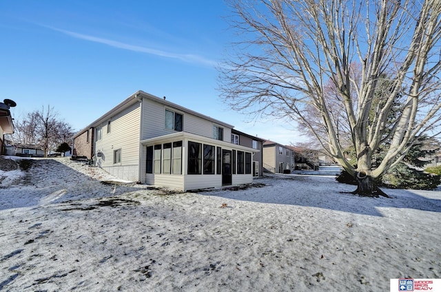 snow covered property featuring a sunroom