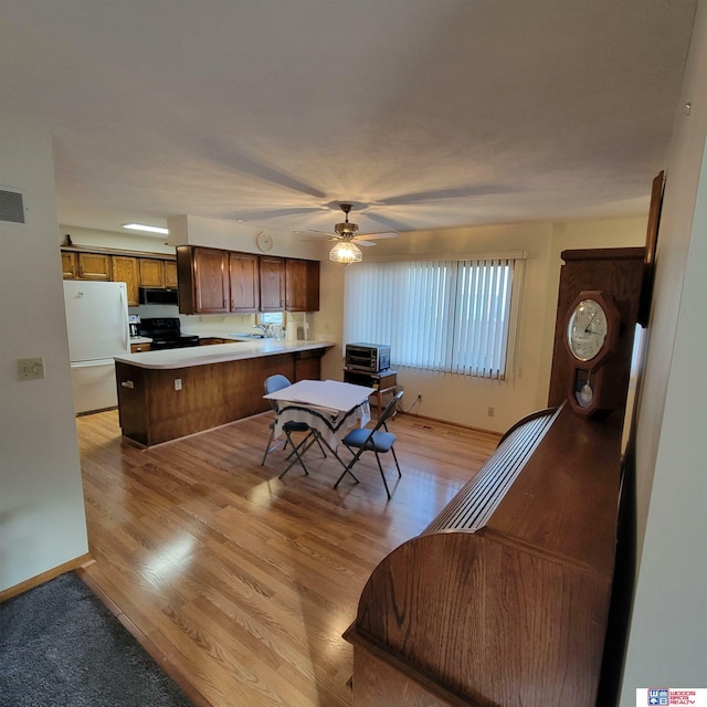 kitchen featuring ceiling fan, sink, kitchen peninsula, light hardwood / wood-style floors, and black appliances