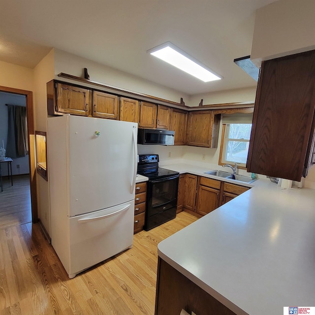 kitchen featuring kitchen peninsula, sink, light hardwood / wood-style flooring, and black appliances