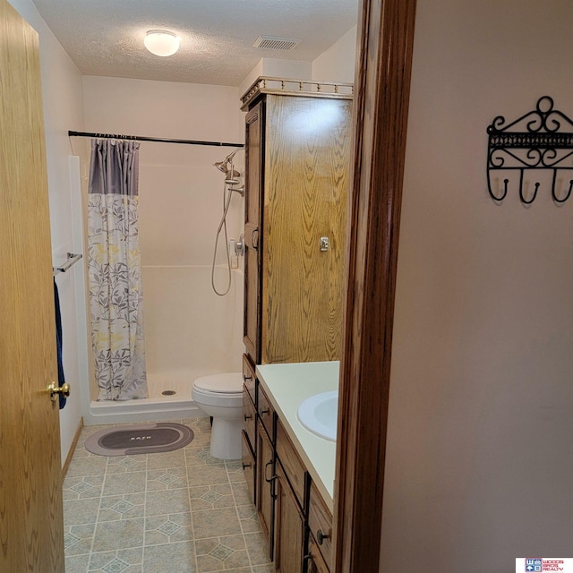 bathroom with a shower with shower curtain, vanity, toilet, and a textured ceiling