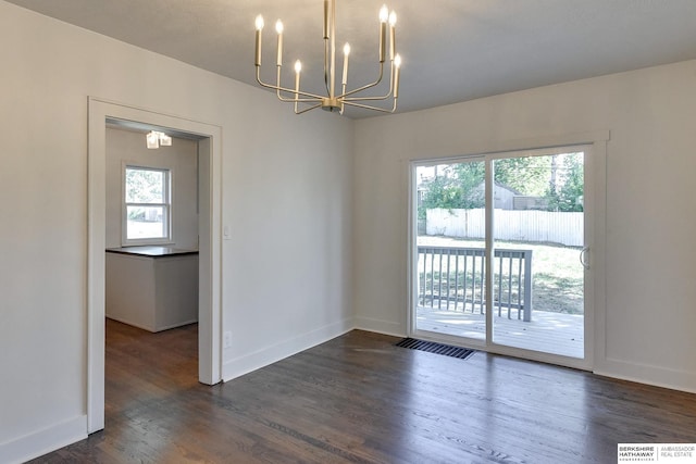 spare room with dark hardwood / wood-style floors and a notable chandelier