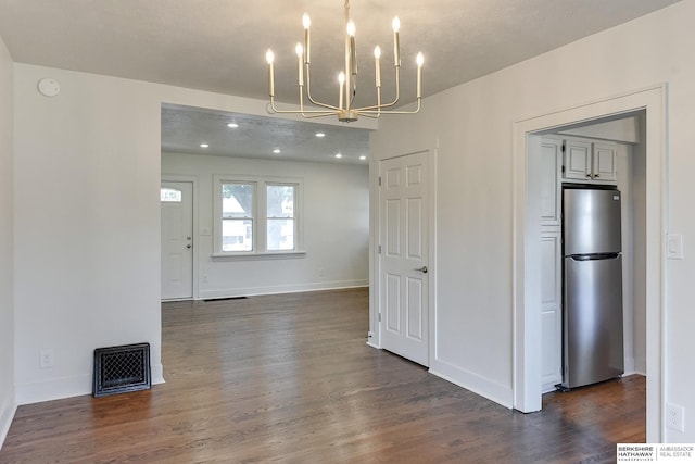 unfurnished dining area with dark hardwood / wood-style floors, a textured ceiling, and an inviting chandelier