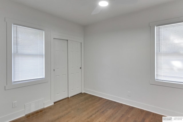 unfurnished bedroom with multiple windows, ceiling fan, a closet, and wood-type flooring